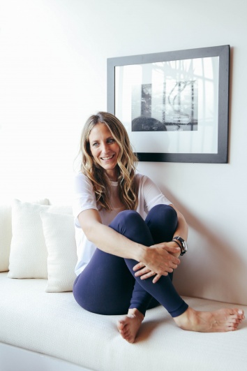 Rachel sitting cross-legged on a white sofa